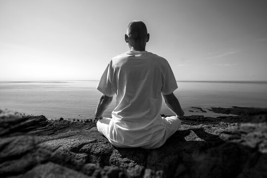 Man meditating in Lotus position by the Atlantic Ocean; Digby, Nova Scotia, Canada