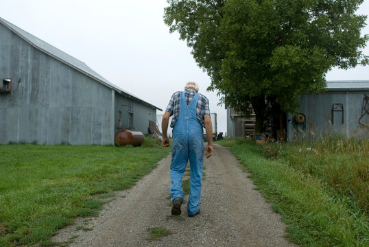 Senior man walks down a dirt road on a farm; Cortland, Nebraska, United States of America