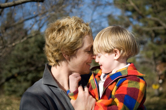 Mother snuggles with her young son outdoors in the sunlight; Cortland, Nebraska, United States of America