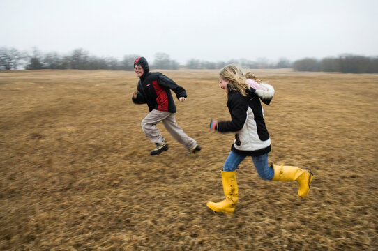 Boy and girl run and chase each other in a field; Lincoln, Nebraska, United States of America.