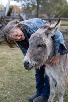 Woman farmer hugging with donkey (Equus asinus) on her farm, Kara's Animals in Beckwith; Ottawa Valley, Ontario, Canada