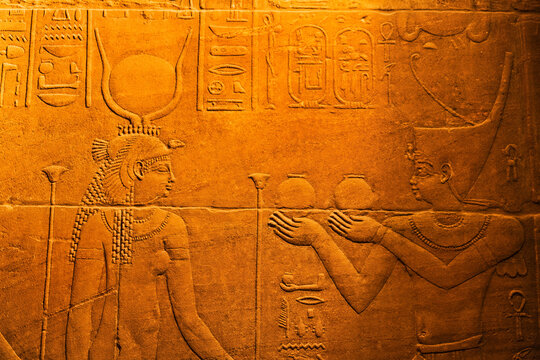 Close-up of bas-relief of hieroglyphs and the Goddess Isis inside the Temple of Isis at Philae Island in the Nile River with golden light; Aswan, Egypt
