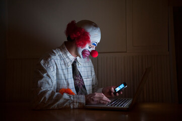 Clown wearing a shirt and tie uses a laptop computer and smart phone simultaneously; Lincoln, Nebraska, United States of America