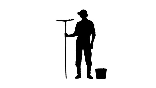 Silhouette of man gardener with bucket and rake standing looking at the garden. Isolated on white background alpha channel.