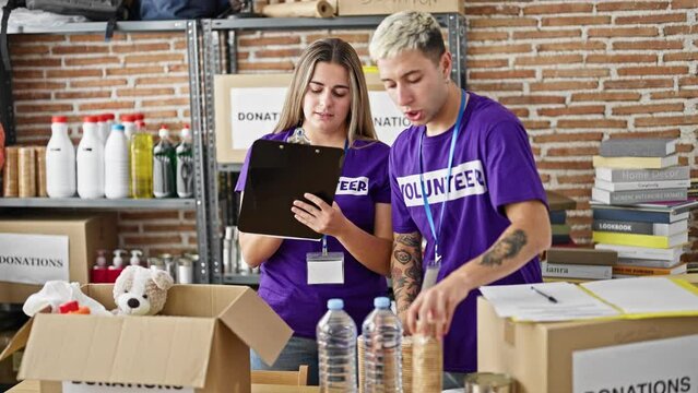 Man and woman volunteers writing on clipboard checking products at charity center