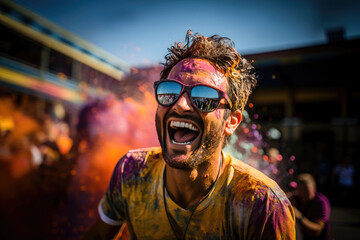 Happy man covered in colorful powder laughing with joy at Holi festival celebration with a crowded background.