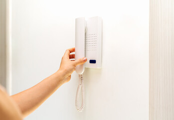 Female person using intercommunication device at her appartment.