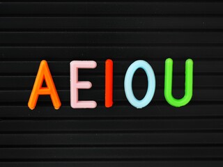 Colorful Aeiou uppercase vowels on a letter board