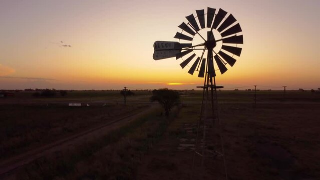 Molino de viento al atardecer en la extensi&oacute;n de la llanura captado por un dron sobrevolando lentamente