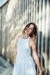 Portrait of a beautiful smiling woman in a summer light dress in the park on a walk