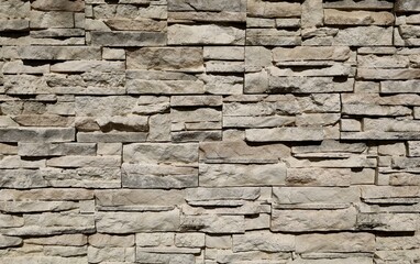 Old stone cladding wall made of striped stacked slabs of  gray brownish rocks. Outdoor coating....