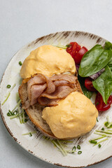 Delicious breakfast - Eggs Benedict with bacon and tomatoes
