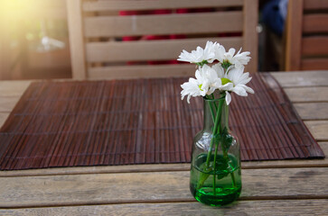 White flowers in a vase on a wooden table in a restaurant
