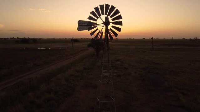 Molino de viento en el ocaso del d&iacute;a tomado por un dron que se va elevando lentamente