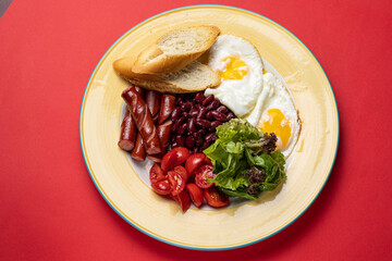 Delicious breakfast - Eggs with sausages, beans, and tomatoes