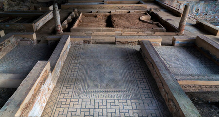 Remains of the archaeological ruins of a Roman mosaic on the floor of a room with blue geometric figures that create a fractal structure in the Mitreo house in Merida, Spain.