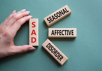 Sad - Seasonal Affective Disorder symbol. Wooden blocks with words Sad. Businessman hand. Beautiful...