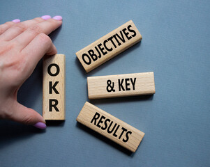 OKR objectives and key results symbol. Wooden blocks with words OKR objectives and key results. Businessman hand. Beautiful grey background. Business and OKR concept. Copy space.