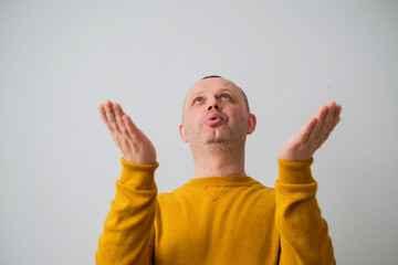 Low angle view of a young man wearing a yellow sweate sending air kiss. Love expression.