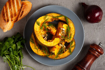 Pumpkin baked in the oven, toast, herbs, onions and spices on a gray background, top vew The concept of healthy eating. The concept of Thanksgiving. Homegrown organic eco food