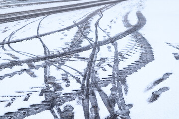 Winter background: traces of people and traces of cars in a snowy parking lot