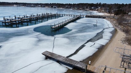 Aerial view of a tranquil winter scene featuring a lake partially covered in ice in Beaver Island © Wirestock