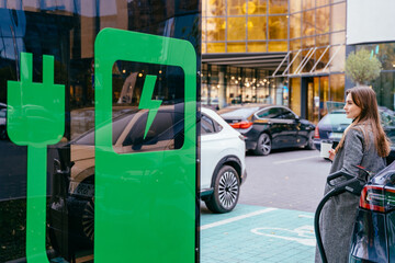Eco friendly rechargeable EV car concept. Charming female waiting electric car to charge. Business...