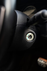 Close-up of a car ignition keyhole with a blurred dashboard background.