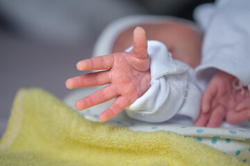 The newborn baby's hand reaches out as if trying to hold something