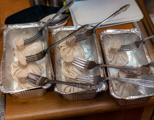 Khinkali and forks in aluminum foil molds close-up on the background of the kitchen table