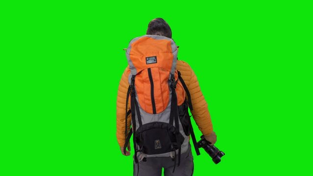 hiker with a mountaineering backpack, holding a camera, admiringly observes the natural landscape around him.standing on a green screen background concept of screen, hiking, trip, freedom
