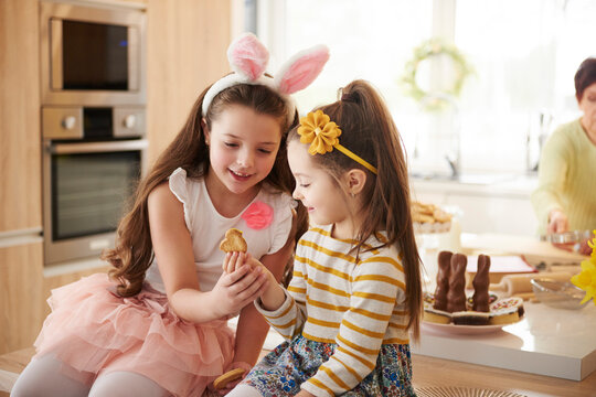 Two girls looking at cookie in kitchen