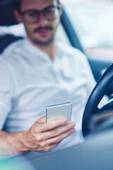 Hand of businessman sitting in car holding cell phone