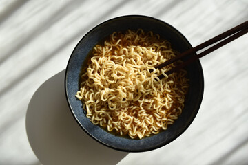 Instant noodles with chopsticks in a bowl. Flat lay top view photo. 