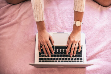 Fototapeta na wymiar Woman's hand using laptop on bed, top view