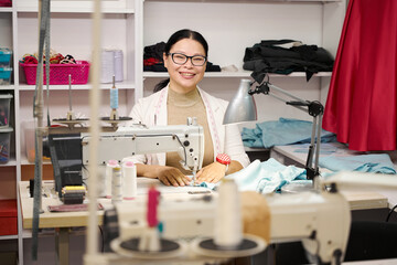 Smiling dressmaker sews on a sewing machine