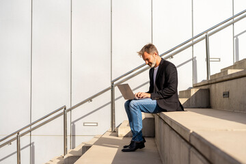 Businessman sitting on steps outdoors using laptop