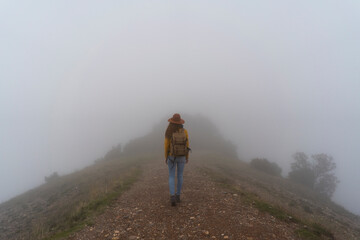 Woman hiking in the fog, walking on a mountain path
