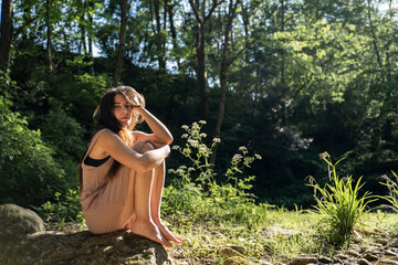 Portrait of young woman sitting on a rock in the forest, Garrotxa, Spain