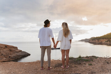 Back view of young couple in love standing in front of the sea, Ibiza, Balearic Islands, Spain