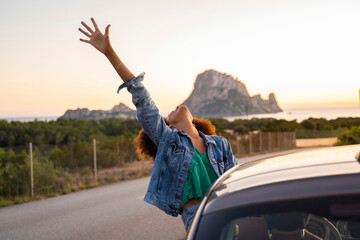 Young woman during road trip with raised arm