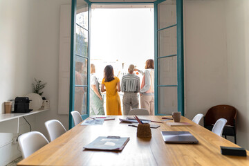 Rear view of four women standing on balcony outside conference room