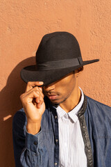 Stylish young man wearing a hat at a wall