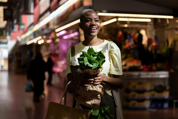 Portrait of happy woman holding paper bag in a market hall