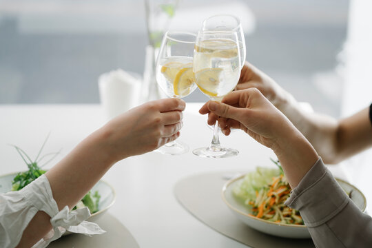 Close-up Of Three Women Toasting Glasses Of Water In A Restaurant