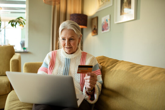 Senior woman paying online expenses with debit card at home