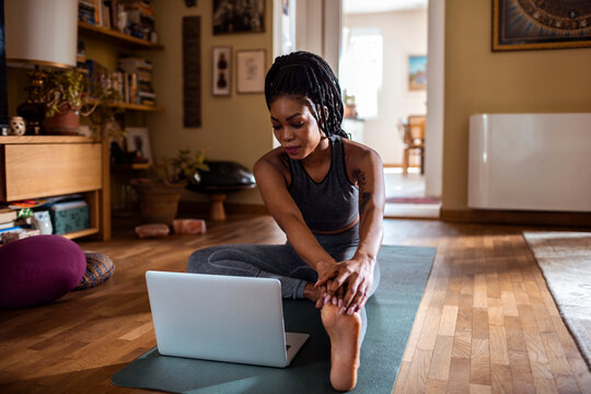 African American Woman Stretching While Watching Online Yoga Class