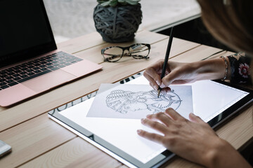 Woman's hand drawing template on light table