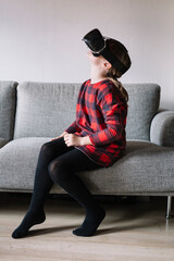 Girl sitting on the couch in the living room using Virtual Reality Glasses