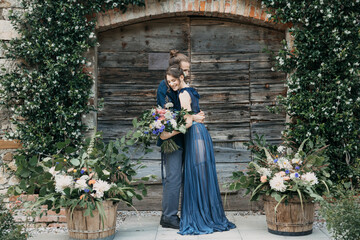 Bride and groom standing at a wooden gate embracing